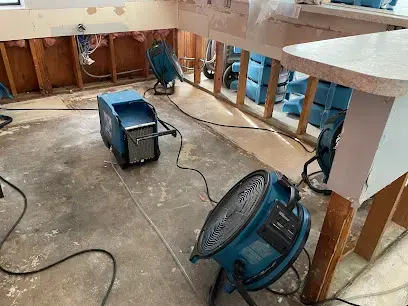 Air movers and a dehumidifier drying a gutted kitchen in La Mesa