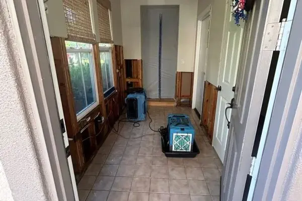 Hallway with baseboards removed and drying equipment running