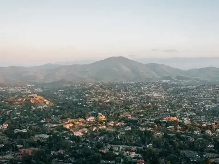 Hillside neighborhoods spread across sloped ground below a coastal mountain in East County San Diego
