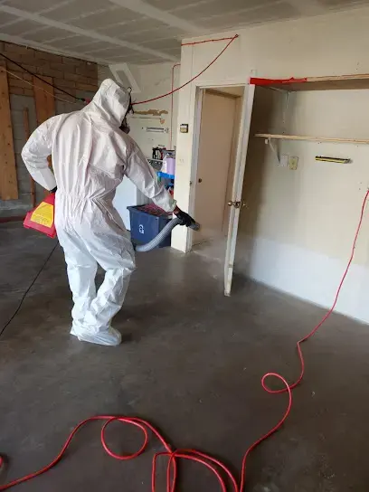 Technician in a protective suit applying antimicrobial treatment after a sewage backup